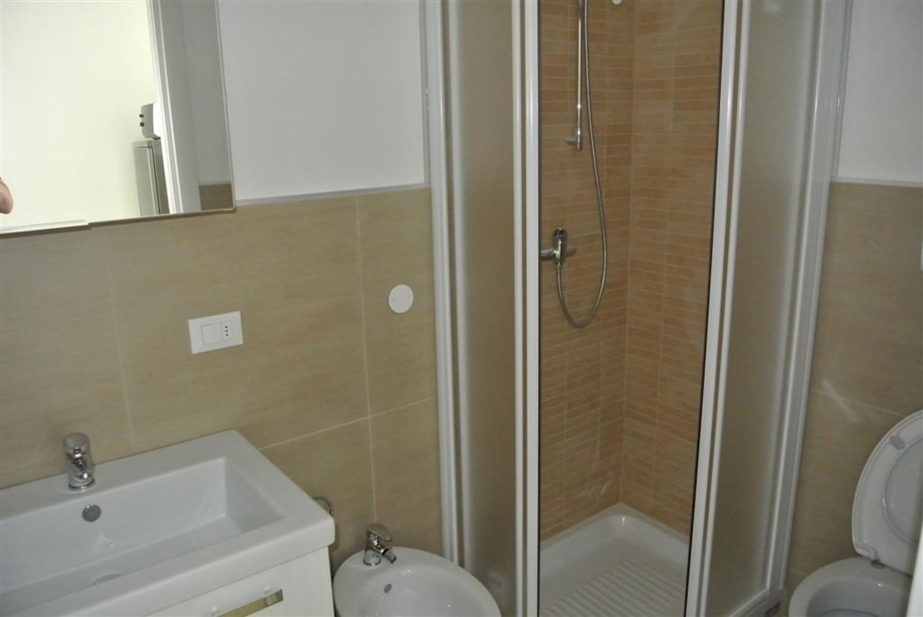A bathroom with a shower, sink, toilet, and a mirror.