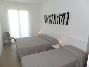 Ein Hotelzimmer mit zwei Betten, einem Sessel und einem Wandbild.