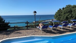 Ein Schwimmbad mit Liegestühlen und Blick aufs Meer.