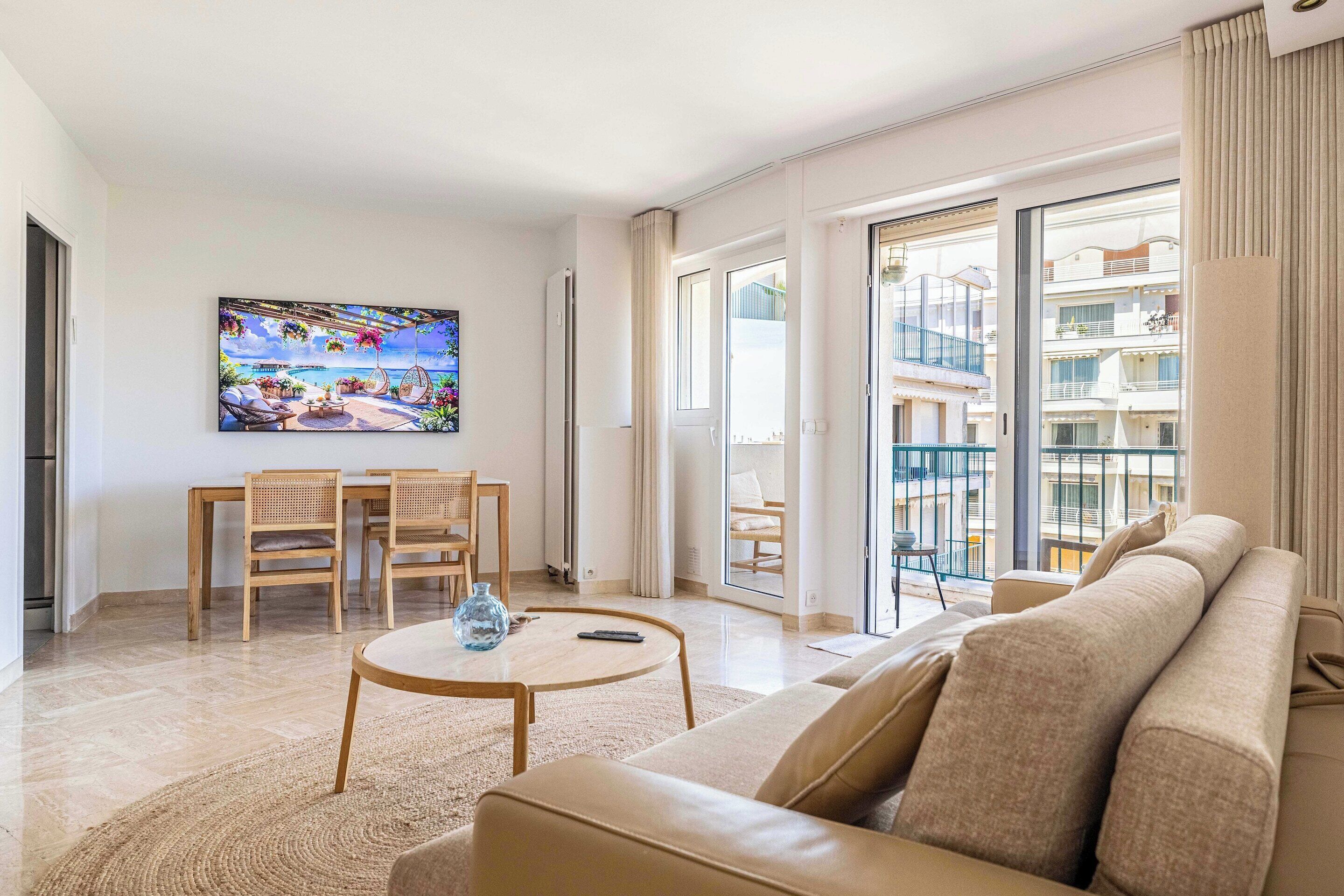 A modern living room with a sofa, a round coffee table, and a dining area with chairs and a table.