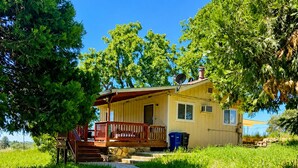 A single-story house with a porch, a stone pathway leading to the entrance, and a blue trash bin beside the house. - Amador Wine Country Farmhouse Near Wineries (Plymouth)