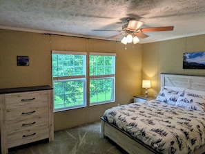 Una camera da letto con un letto, un comodino, una cassettiera, una ventola a soffitto e una finestra.