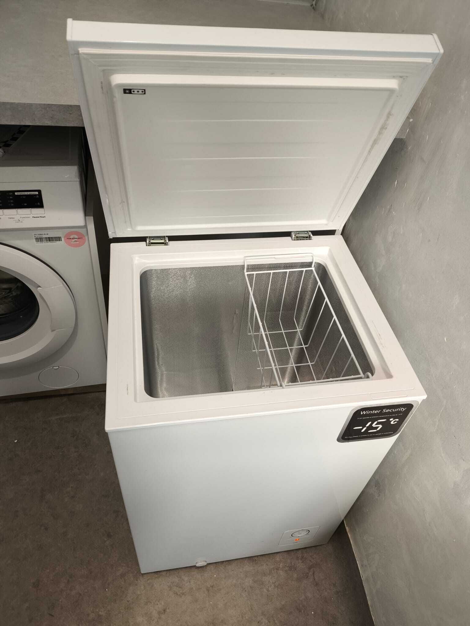 Um mini-refrigerador branco com visor digital indicando -15°C, compartimento para congelamento e painel de controle com botões.