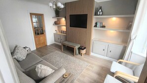 A modern living room with a sofa, coffee table, TV, and built-in shelving.