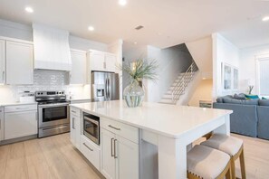 A modern kitchen with white cabinetry, stainless steel appliances, and a central island with seating. - Gulf-Front Luxury Home with Private Pool, Beach Access & Bikes! (Panama City Beach)