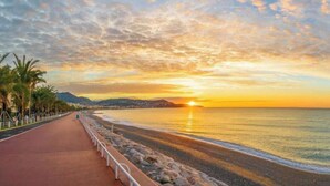 A coastal sunset view with a paved walkway, palm trees, and a calm sea. - Apt 4 guests Promenade des Anglais (Nice)