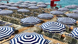 A beach with numerous striped umbrellas and lounge chairs. - Apt 4 guests Promenade des Anglais (Nice)