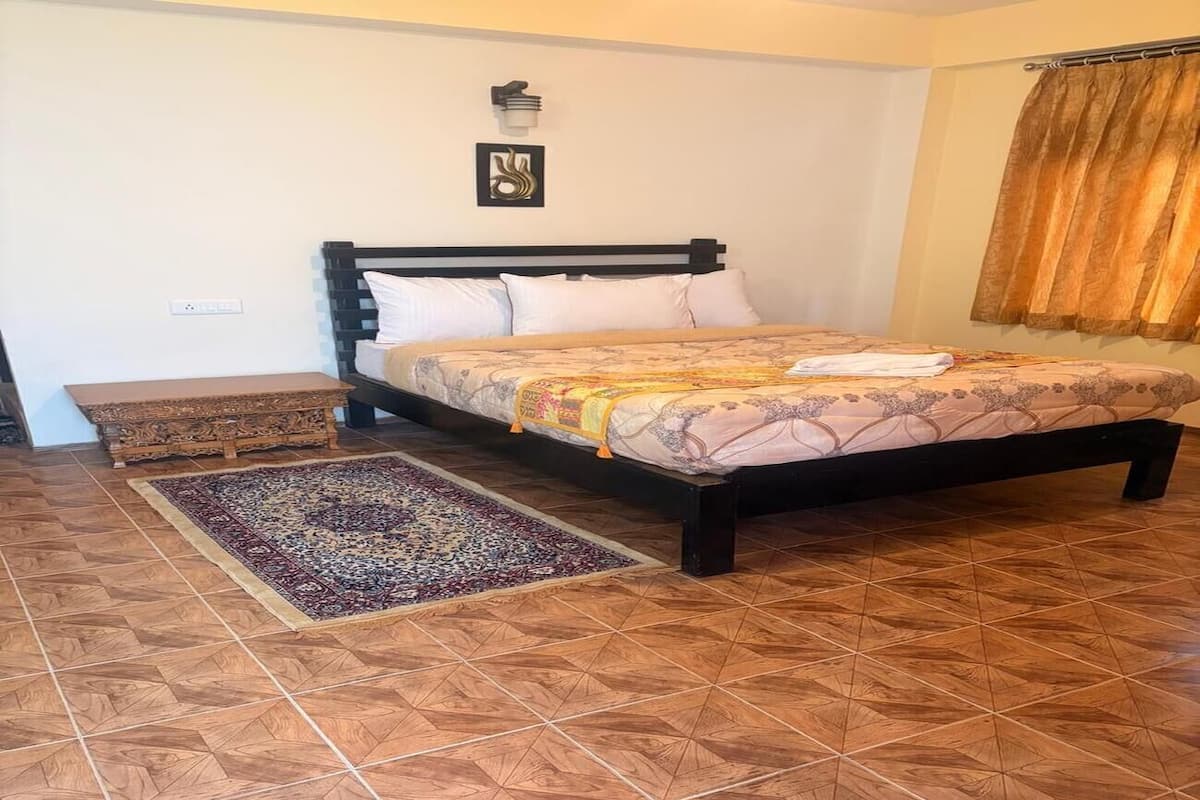 A bedroom with a bed, a rug, and a wall-mounted light fixture.