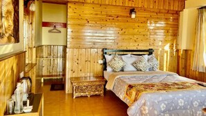 A wooden-paneled room with a bed, a hanging light fixture, and a wall-mounted coat rack.