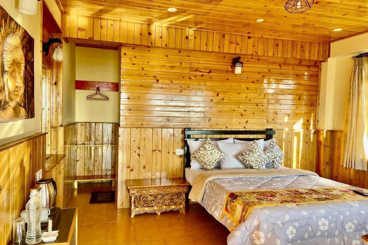 A wooden-paneled room with a bed, a hanging light fixture, and a wall-mounted coat rack.