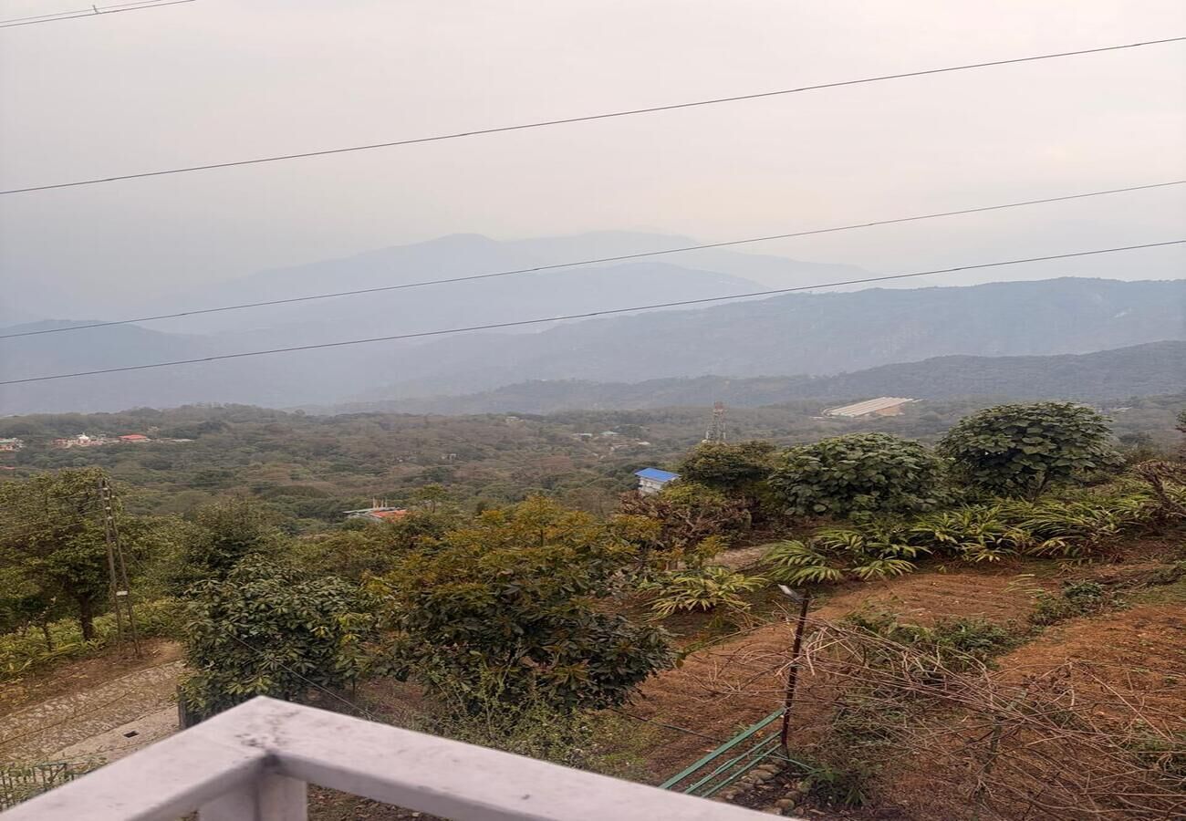 Une vue d’un paysage vallonné, avec de la végétation et des bâtiments situés au loin.