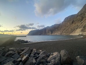Eine Küstenlandschaft mit felsigem Vordergrund, einem Strand und einer Klippe.