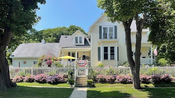 A two-story house with a white picket fence, a front porch, and a flag.
