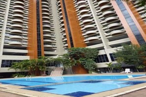 Ein Hochhaus mit mehreren Balkonen, einem Pool und umliegender Bepflanzung.
