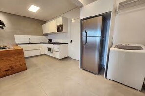 Eine moderne Küche mit weißen Schränken, einem Edelstahlkühlschrank und einer Holz Arbeitsplatte.