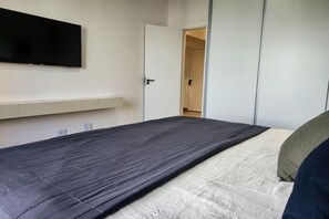 Ein Schlafzimmer mit Bett, einem an der Wand montierten Fernseher und einem Kleiderschrank.
