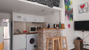 Una cocina compacta con lavadora, microondas y televisor.