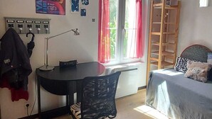 Una habitación con escritorio, silla, cama y ventana con cortinas.