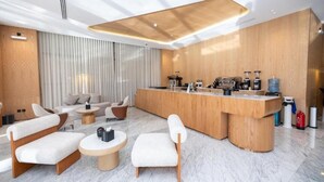 A modern hotel lobby with a reception desk, seating area, and a large window with blinds. - 7Crown Tahliah Hotel (Riyadh)