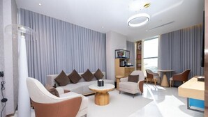 A modern living room with a sofa, armchairs, a coffee table, and a dining area. - 7Crown Tahliah Hotel (Riyadh)