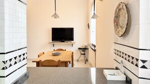 Een moderne keuken met een televisie, een houten eettafel en een betegelde vloer.