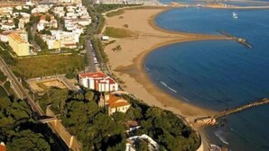 An aerial view of a coastal area with a beach, buildings, and a pier. - Cosy aparment 200 meters from the beach (Vilanova i la Geltrú)