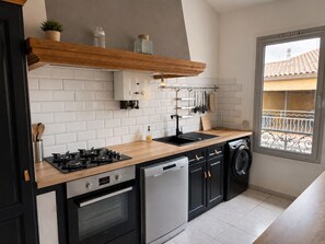 Eine kompakte Küche mit Geschirrspüler, Backofen und Fenster mit Balkonblick.