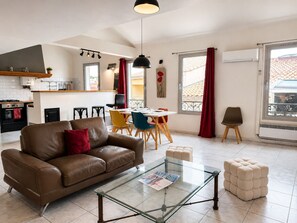 Ein modernes Wohnzimmer mit einer Ledersofa, einem Glastisch und einem Essbereich mit Tisch und Stühlen.