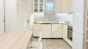 Une cuisine de taille réduite comprenant une table à manger, des chaises, une fenêtre et un réfrigérateur.