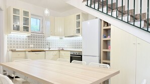 Une cuisine moderne avec une table en bois, des chaises blanches et un escalier.