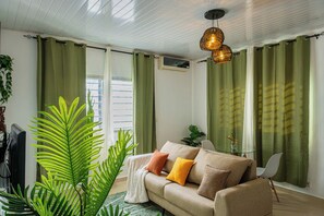 A living room with a sofa, a television, and green curtains.