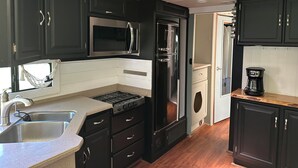 Una cocina compacta con estufa, microondas, refrigerador y cafetera.