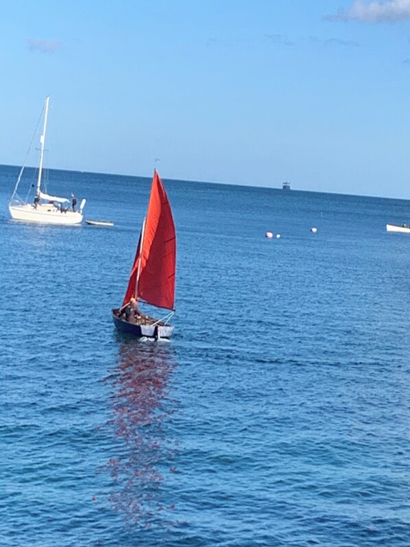 A sailboat with a red sail on calm blue water. - Westcroft at Seasound (Kingsand)