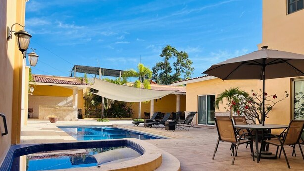 Una piscina amb una banyera d'hidromassatge, zones d'estar a l'exterior i un porxo cobert.