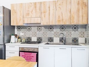A kitchen with wooden cabinets, a gas stove, a sink, and patterned backsplash tiles.
