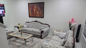 A living room with a sofa, armchair, coffee table, and a painting on the wall. - The Blessed Family Home-2bed Rooms 2washrooms (Edmonton)