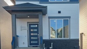 A two-story house with a front porch, a garage, and a driveway. - The Blessed Family Home-2bed Rooms 2washrooms (Edmonton)