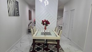 A dining area with a glass-top table, chairs, a patterned rug, and a vase of flowers. - The Blessed Family Home-2bed Rooms 2washrooms (Edmonton)