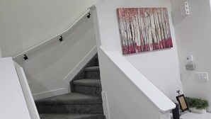 A staircase with a grey carpet, white walls, and a painting of trees. - The Blessed Family Home-2bed Rooms 2washrooms (Edmonton)
