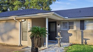 A single-story house with a covered porch, a mailbox, and a small palm tree in the front yard. - Family-Friendly 3BR/2BA Rental in Nederland (nederland)
