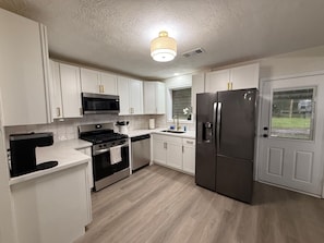 A modern kitchen with white cabinets, stainless steel appliances, and a wooden floor. - 3-bedroom 2-bath home in Beaumont (Beaumont)