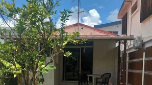 Una propiedad residencial con un camino pavimentado que conduce a un patio cubierto con mesa y sillas.