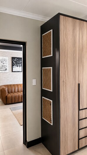 Ein Zimmer mit einem braunen Ledersofa, einer schwarzen Holzkommode und gerahmten Kunstwerken an der Wand.