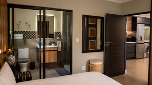 Ein modernes Hotelzimmer mit Bett, Bad mit Dusche, einer Küchenzeile und einem Essbereich.