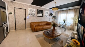 Ein modernes Wohnzimmer mit einem braunen Ledersofa, einem runden Couchtisch und einem Essbereich mit einem Glastisch und Stühlen.