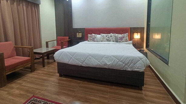 A hotel room with a bed, a chair, a small table, a wall-mounted TV, and a ceiling light. - Hotel O Aura Mall Bhopal (Bhopal)