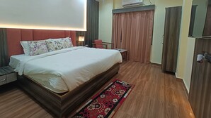 A hotel room with a large bed, a desk, a chair, a wardrobe, and an air conditioning unit. - Hotel O Aura Mall Bhopal (Bhopal)