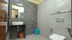 A bathroom with a sink, mirror, toilet, and a blue bucket. - Hotel O Aura Mall Bhopal (Bhopal)