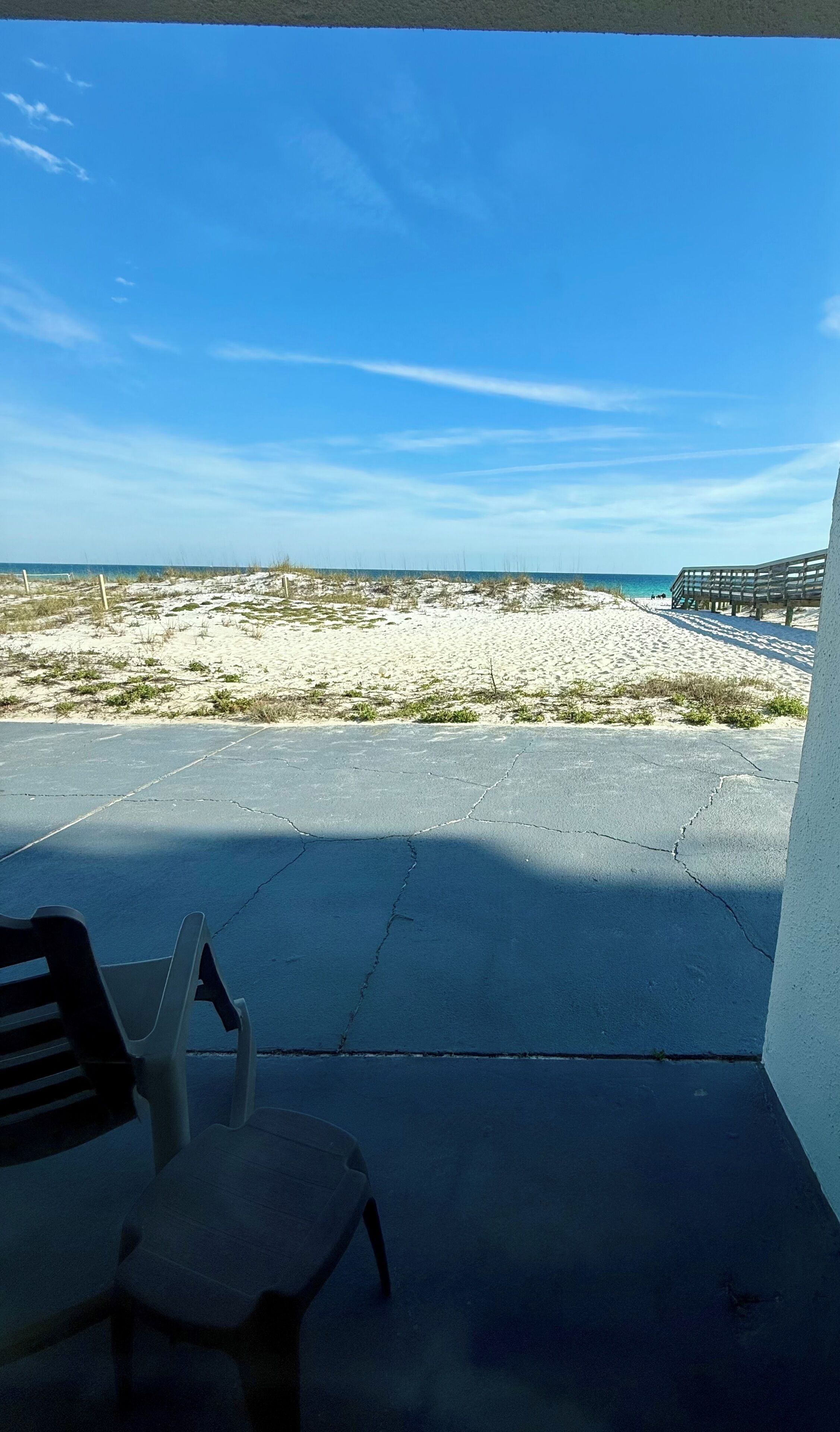 Un balcon donnant sur une plage et une promenade en bois.