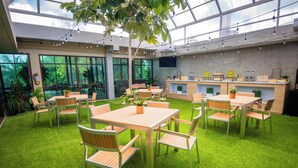 Amplio espacio interior con mesas, sillas, una recepción y ventanas grandes.